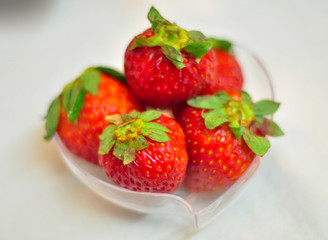 Fresh strawberries in a small heart-shaped plastic container