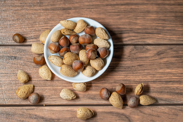 frutos secos mixto de almendras y avellana sobre un bowl de color blanco en una tabla marrón