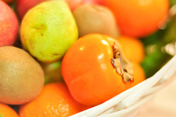 Fruit basket close up with persimmon, pear, kiwi and clemantine