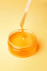 Honey in a jar on a yellow background flows, spatulas for depilation, natural wax for depilation