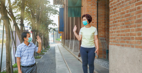 Asian middle aged people wearing mask and keep social distancing to avoid the spread of COVID-19