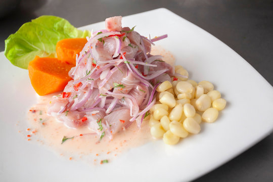 Peruvian seafood: fish cebiche with onion, chili, sweet corn and sweet potato served on a white plate