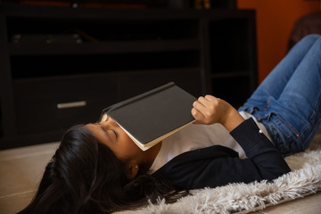 Obraz premium girl lying on a mat with notebook sleeping at home wearing white t-shirt and blue sweater and jeans coronavirus and pandemic quarantine in mexico