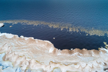 Top view of the melting snow on the shore of Ladoga Lake on a March day (aerial photography). Leningrad region, Russia
