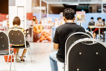Back view of people order food and wait to take home inside of department store closed due to the coronavirus (Covid-19), Restaurants set chairs for social distancing to waiting for the food.