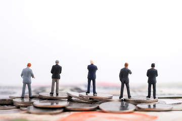 Miniature people : Many of businessman standing on the coin and banknote (US dollar, Singapore dollar) isolated on white background with copy space. Money, business finance, oil and stock concept