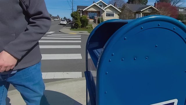 Man sends letter in public mailbox on the sidewalk