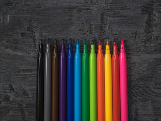 A set of neatly stacked colored markers on a wooden background.