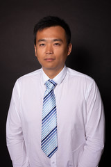 Young asian man in business white shirt with tie looking seriously at camera