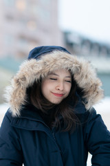 Portrait of woman wearing warm coat with fur hood, having fun in winter