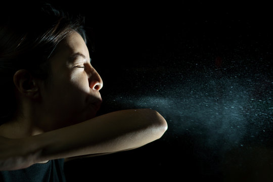 Woman coughing or sneezing in her elbow. Concept of stop spread of the virus. Spray infection