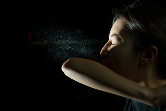 Woman coughing or sneezing in her elbow. Concept of stop spread of the virus. Spray infection