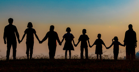 The shadow of a happy family holding hands in the meadow during sunset Happy family enjoying life together outdoors Round dance celebration ceremony
