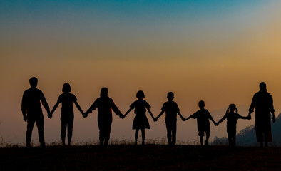 The shadow of a happy family holding hands in the meadow during sunset Happy family enjoying life together outdoors Round dance celebration ceremony