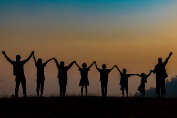 The shadow of a happy family holding hands in the meadow during sunset Happy family enjoying life together outdoors Round dance celebration ceremony