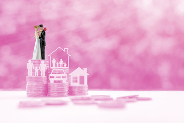 Miniature figurine couple on steps of rising coins on pink background