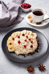 Oatmeal with milk with banana cranberries and sesame seeds. A Cup of coffee, healthy Breakfast Concept.