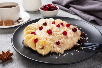Oatmeal with milk with banana cranberries and sesame seeds. A Cup of coffee, healthy Breakfast Concept.