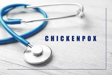 Stethoscope on wooden background, closeup. Chickenpox disease
