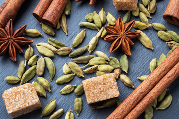 Whole grains of cardamom, a stick of cinnamon star anise and cane sugar. Close up. Ingredients for making the Indian drink masala tea.