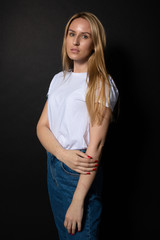 Young caucasian woman calmly, seriously looks. Black backgroung. Human portrait