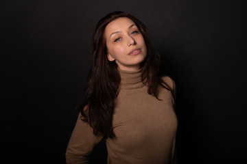 Attractive girl calmly looks at camera. Isolated black background