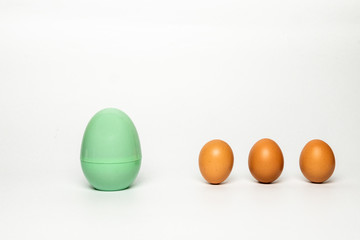 Eggs model in green color placing far from other eggs isolated on white background. Concept of medical isolation and social distances for Covid-19 pandemic.