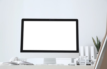Modern computer with blank screen on table near white wall. Space for design