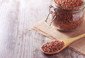 Buckwheat groats in a wooden spoon. Close-up.