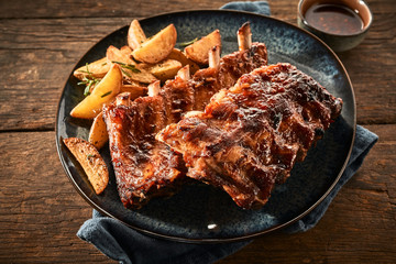 Close up of barbecued ribs and wedges on timber