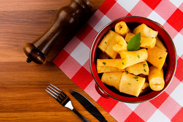 Portion of cassava fried in red pan on wooden table.