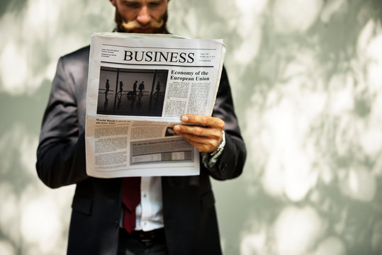Businessman standing and reading newspaper