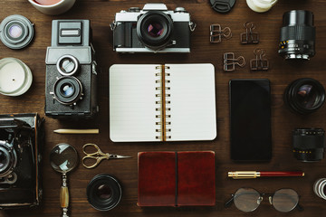 Vintage film camera, lenses and stationery on dark wooden table, rustic flatlay
