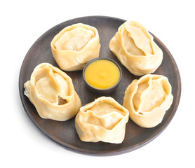 Plate with oriental dumplings and sauce on white background