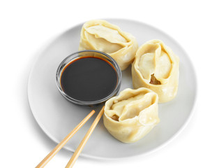Plate with oriental dumplings and sauce on white background