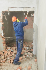 demolition work and rearrangement. worker with sledgehammer destroying wall