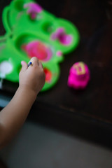Toddler hand mixing colour in the water colour pallet. Top view.