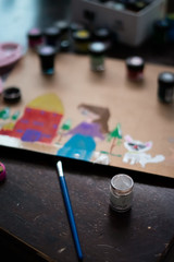 Paintbrush painting with water colours on the table.