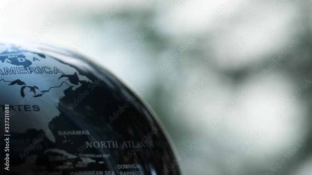 Wall mural macro of a spinning earth globe with a forest background in slow motion