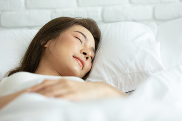 Beautiful woman sleeping on white bed in the bedroom,sweet dreams, keeps eyes closed, enjoys good...