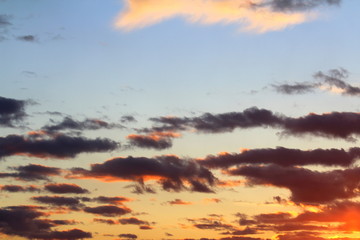 Clouds in the blue sky at sunset or dawn backlit by the sun. Place for text and design.