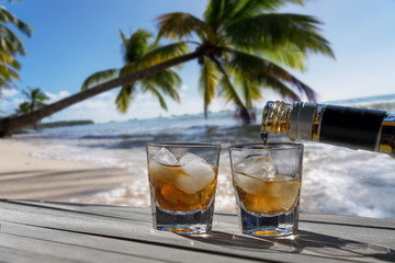 Drink for two on a Caribbean beach. Two glasses of liquor for a carefree vacation concept for a couple - Palms outstretched on the sea.