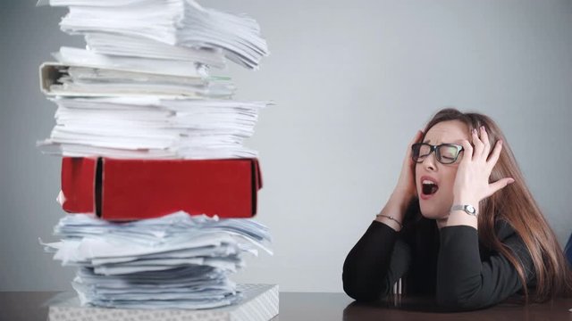 Stressed financial manager looking at the pile of unfilled paper sheets and screaming in anger.