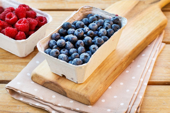 Paper boxes with raw fruits. Hand picked blueberries and raspberries.