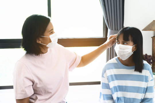 Mom checking her daugther Temperature. They are under surgical face mask covering mouth and nose. Awareness and Watch out Corona Virus or COVID-19 concept.