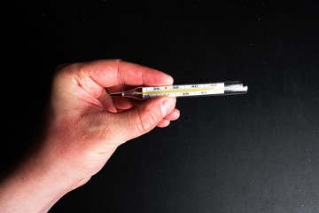 Male hands holding a thermometer with high temperature