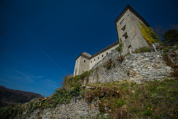 Naklejka premium View of partially restored medieval castle of Kostel in the village of Kostel, close to Kolpa, Slovenia, on a sunny day with clear blue sky. Beautiful castle panorama.