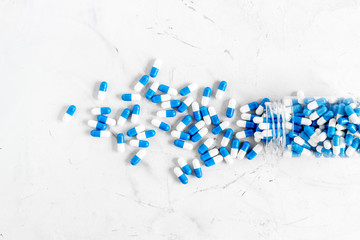 Blue and white capsules poured from a bottle - sports supplement creatine - on white background top view