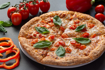 Pizza Margarita on a black background with tomatoes and mozzarella. Still-life.