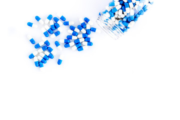 Blue and white capsules poured from a bottle - sports supplement creatine - on white background top view copy space